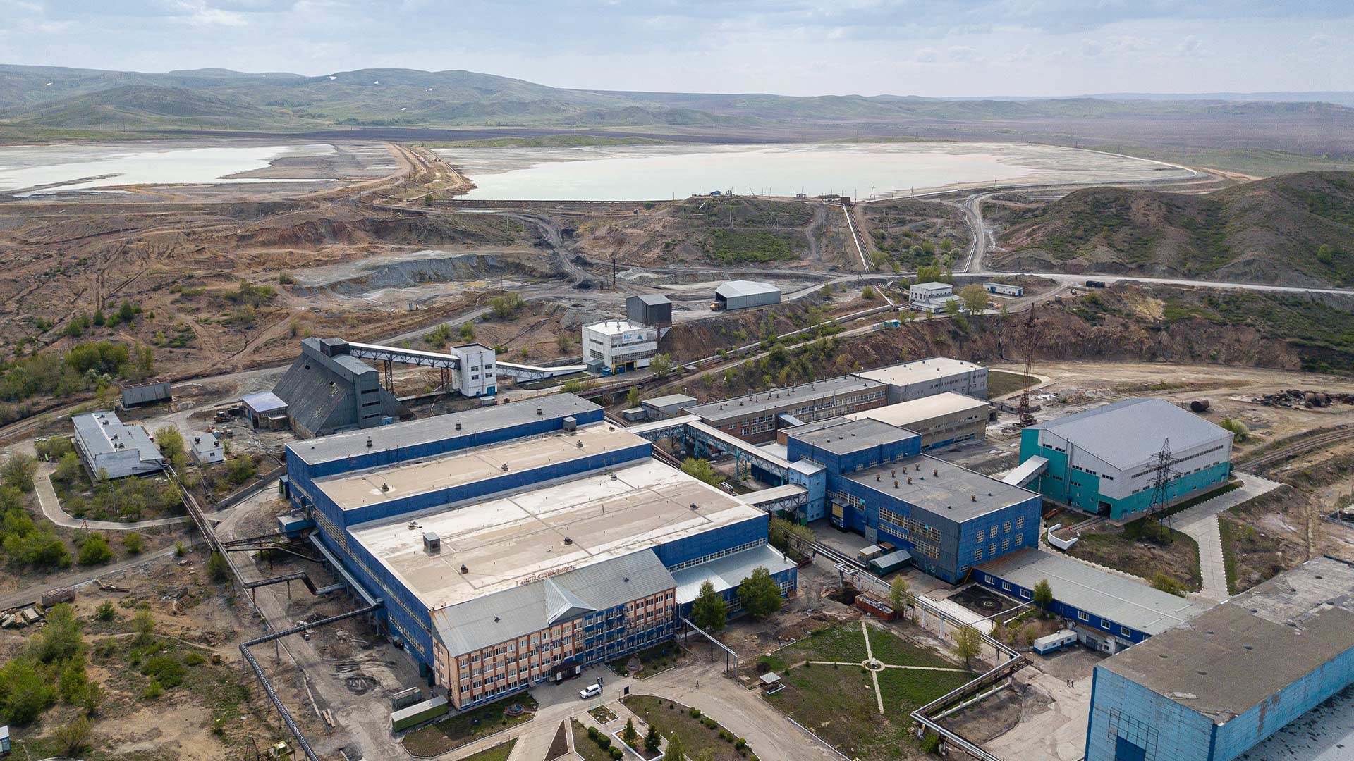 Drone style view of East Region mining facilities. A body of water can be seen in the distance. 