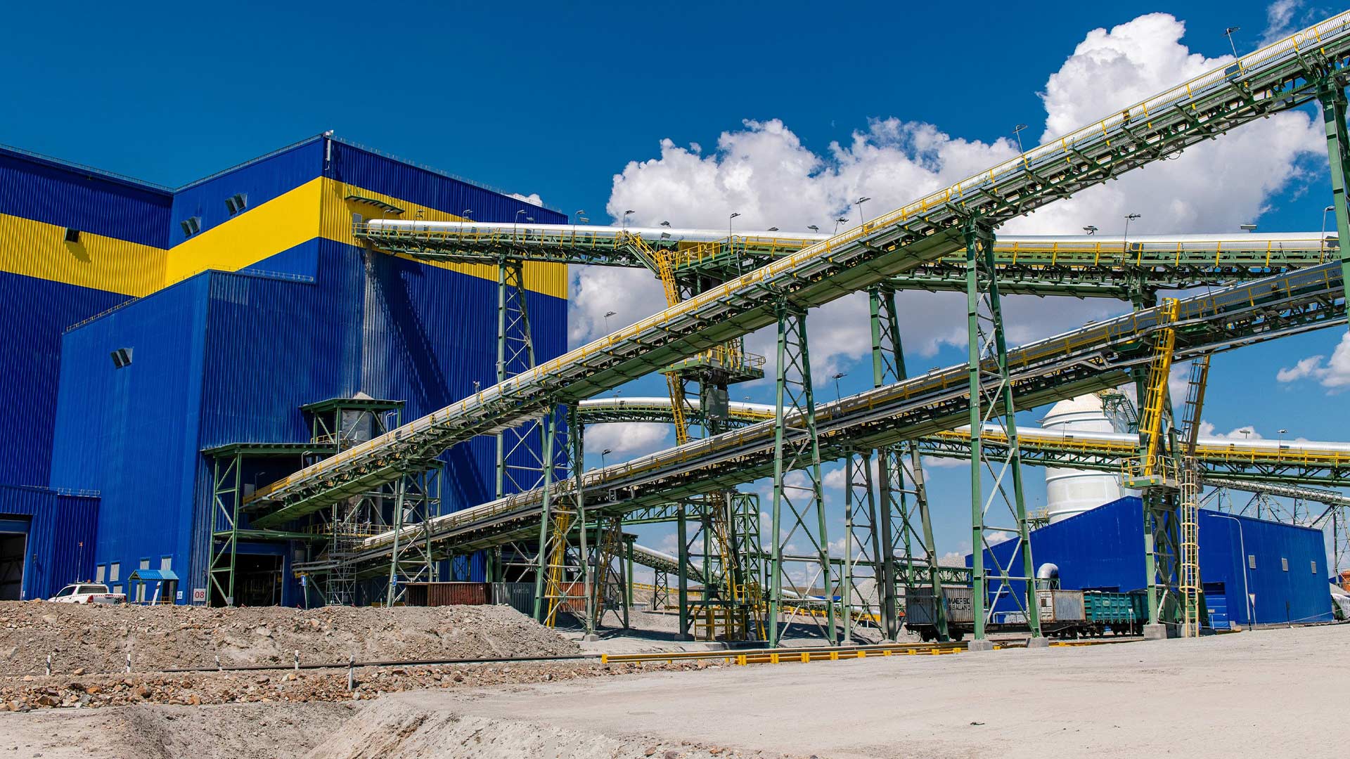 The outside of a mining facility. Large tubes are seen transporting materials into the building. 