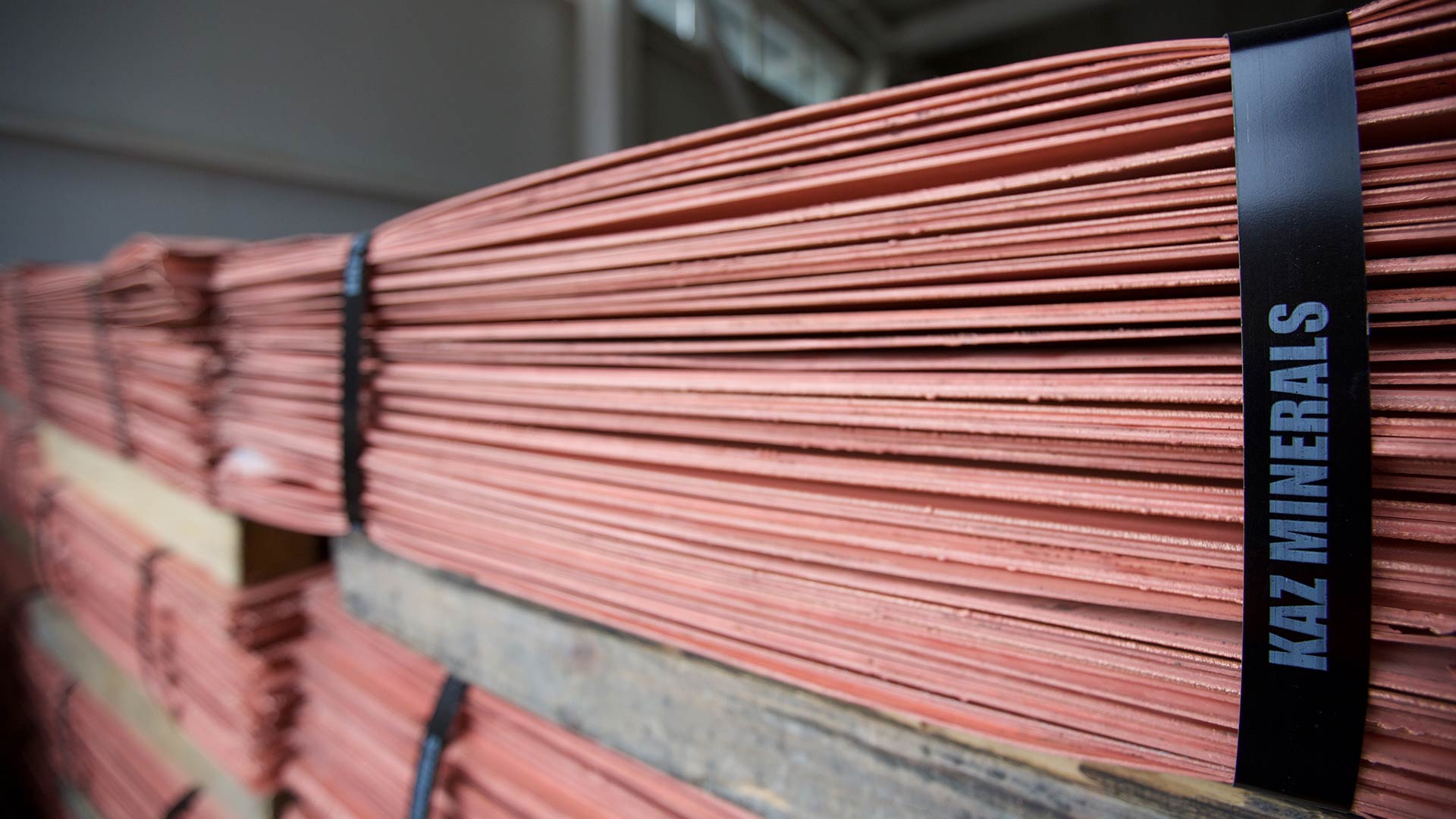 Sheets of copper piled on top of one another and secured with black bands.