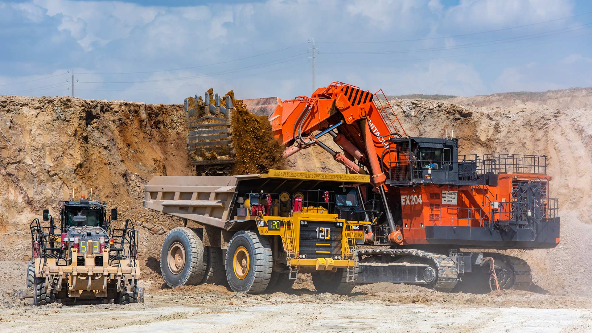Multiple heavy duty drilling machines set against desert-like background and blue sky.