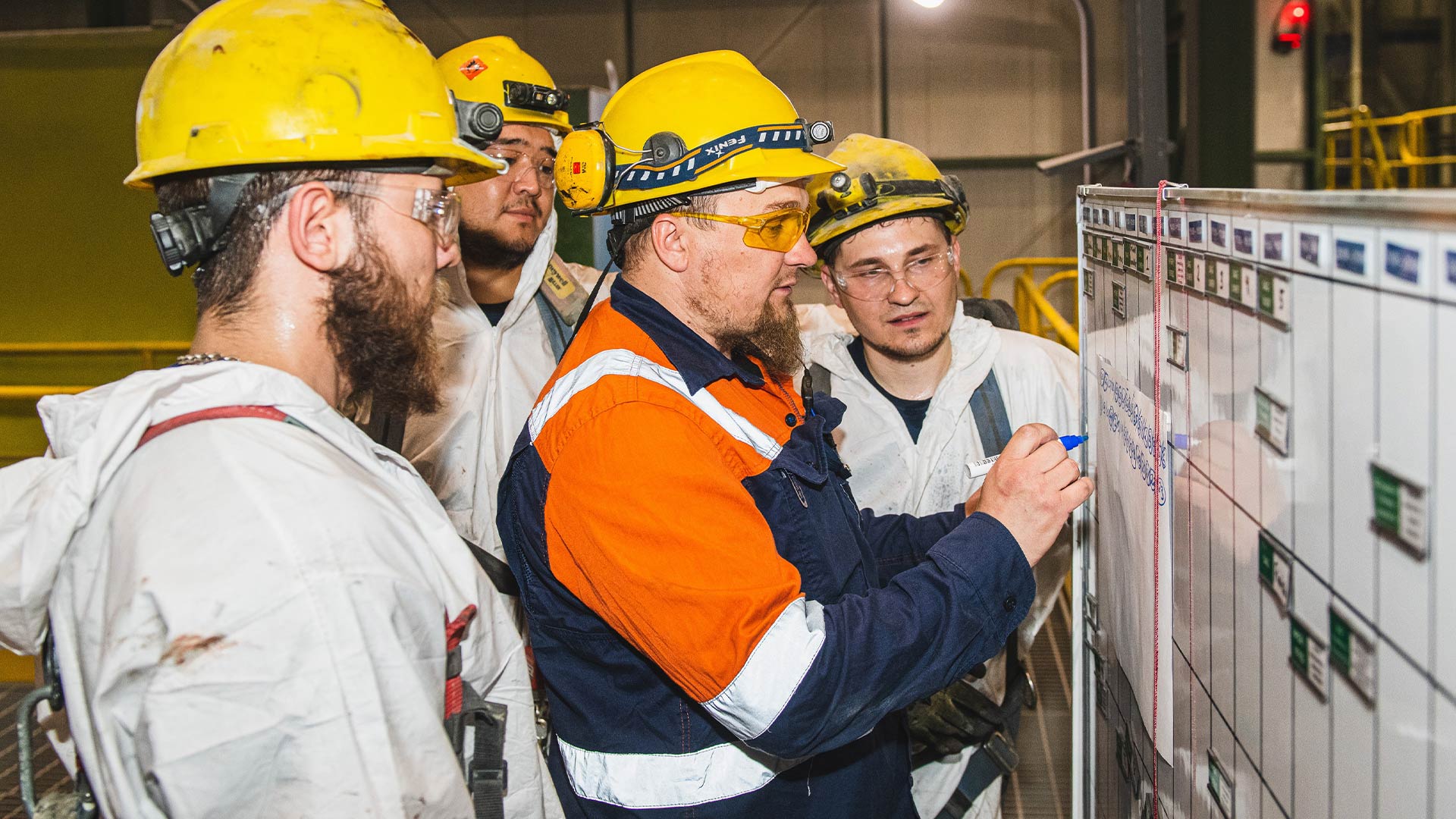 Several workers gathered around a white board. 