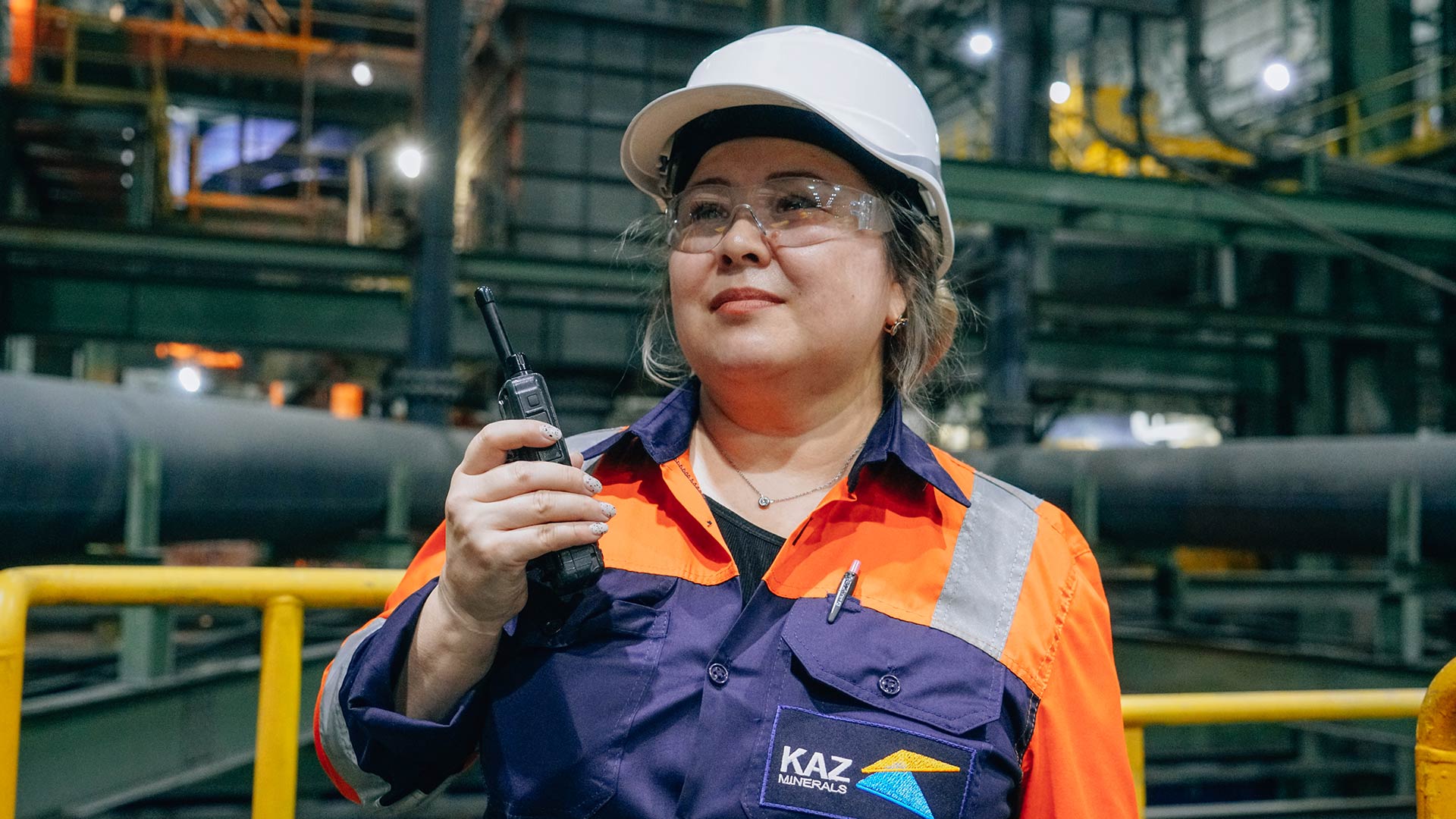 Қауіпсіздік киімін киген екі жұмысшы бірге жұмыс істейді.